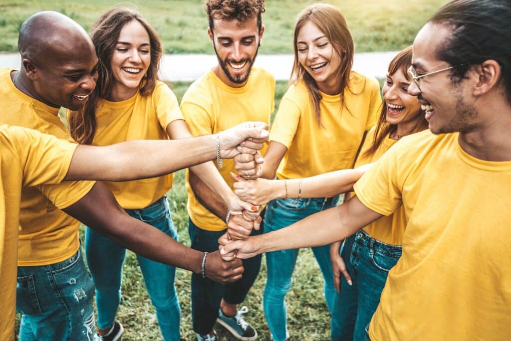 Multiracial happy young people stacking hands outside - Youth community concept with guys and girls standing together supporting each other