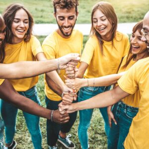 Multiracial happy young people stacking hands outside - Youth community concept with guys and girls standing together supporting each other
